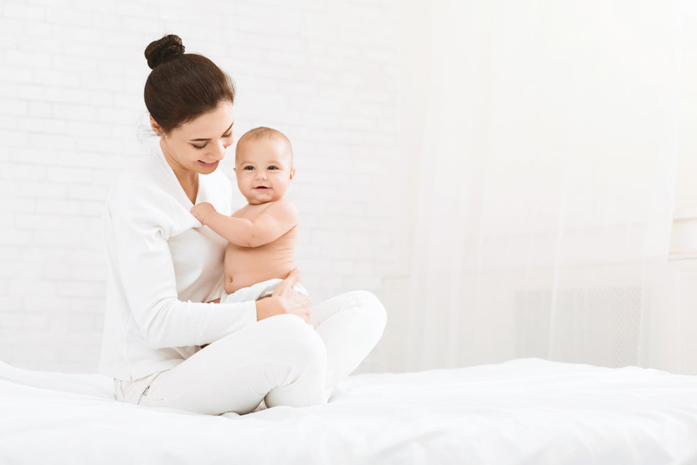 Mother holding smiling baby on a bed