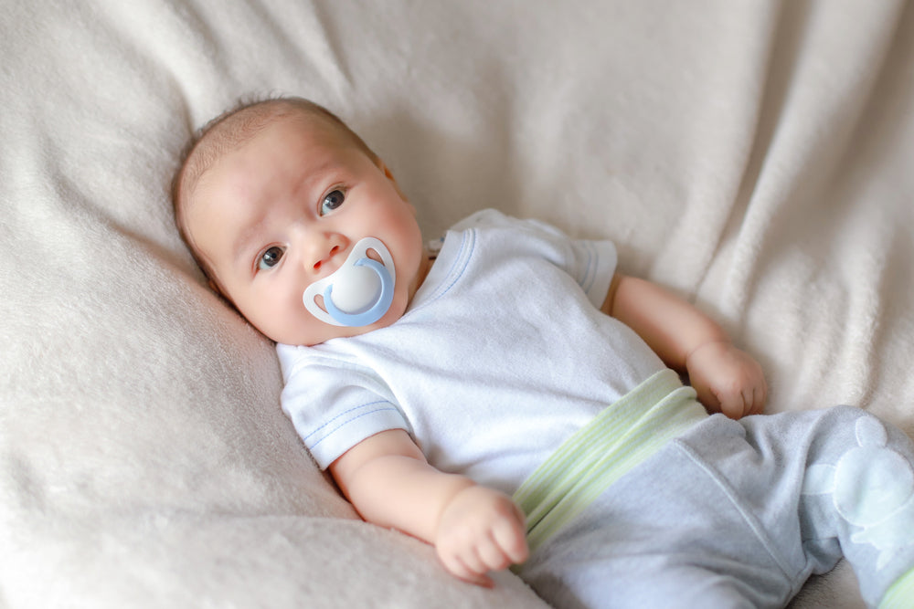 Baby lying on a blanket with a pacifier
