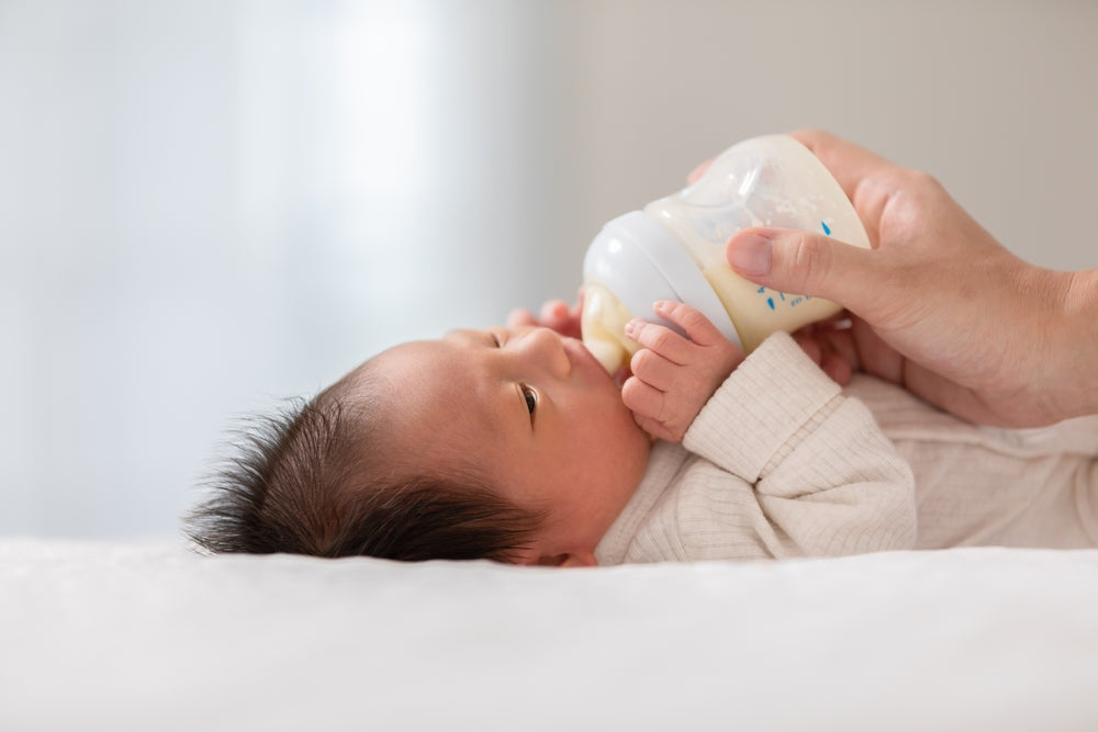 Baby drinking milk from a bottle while lying down