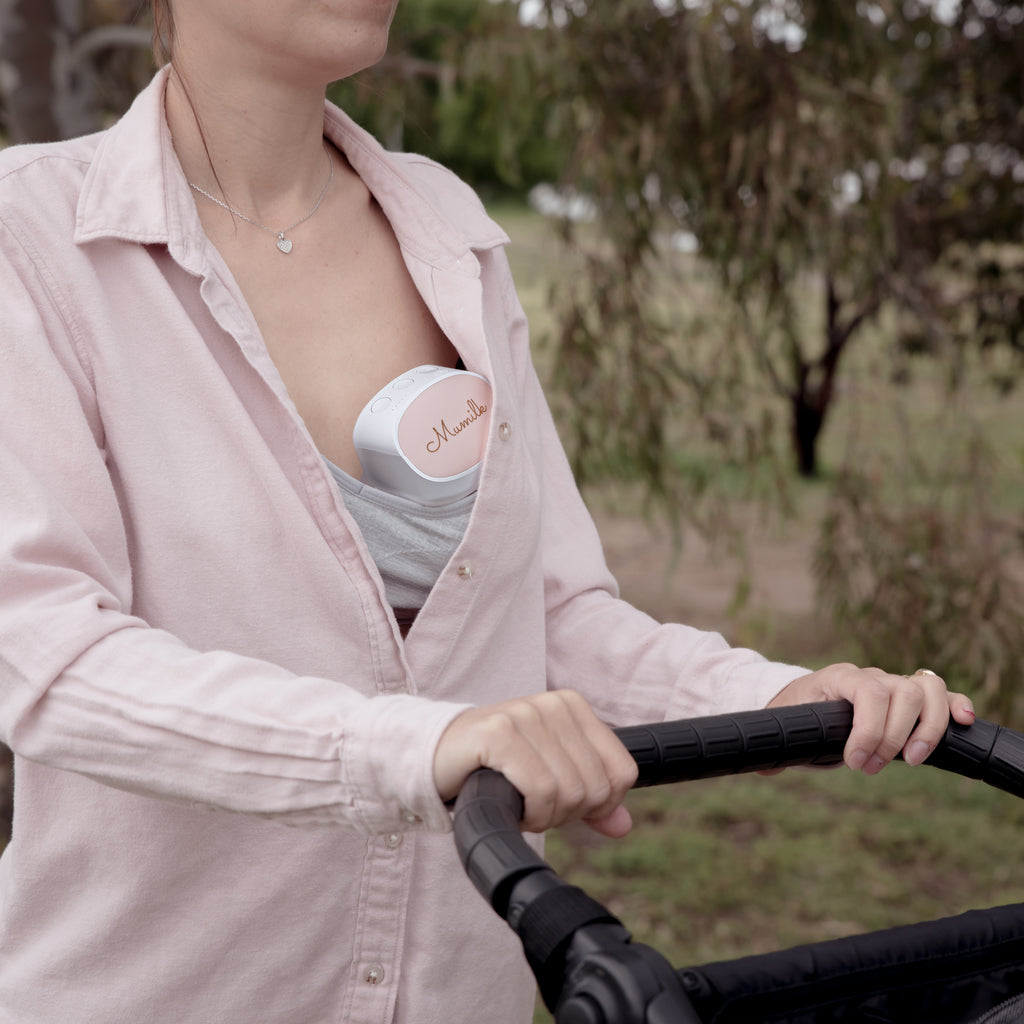 woman wearing a mumilk portable breast pump while strolling