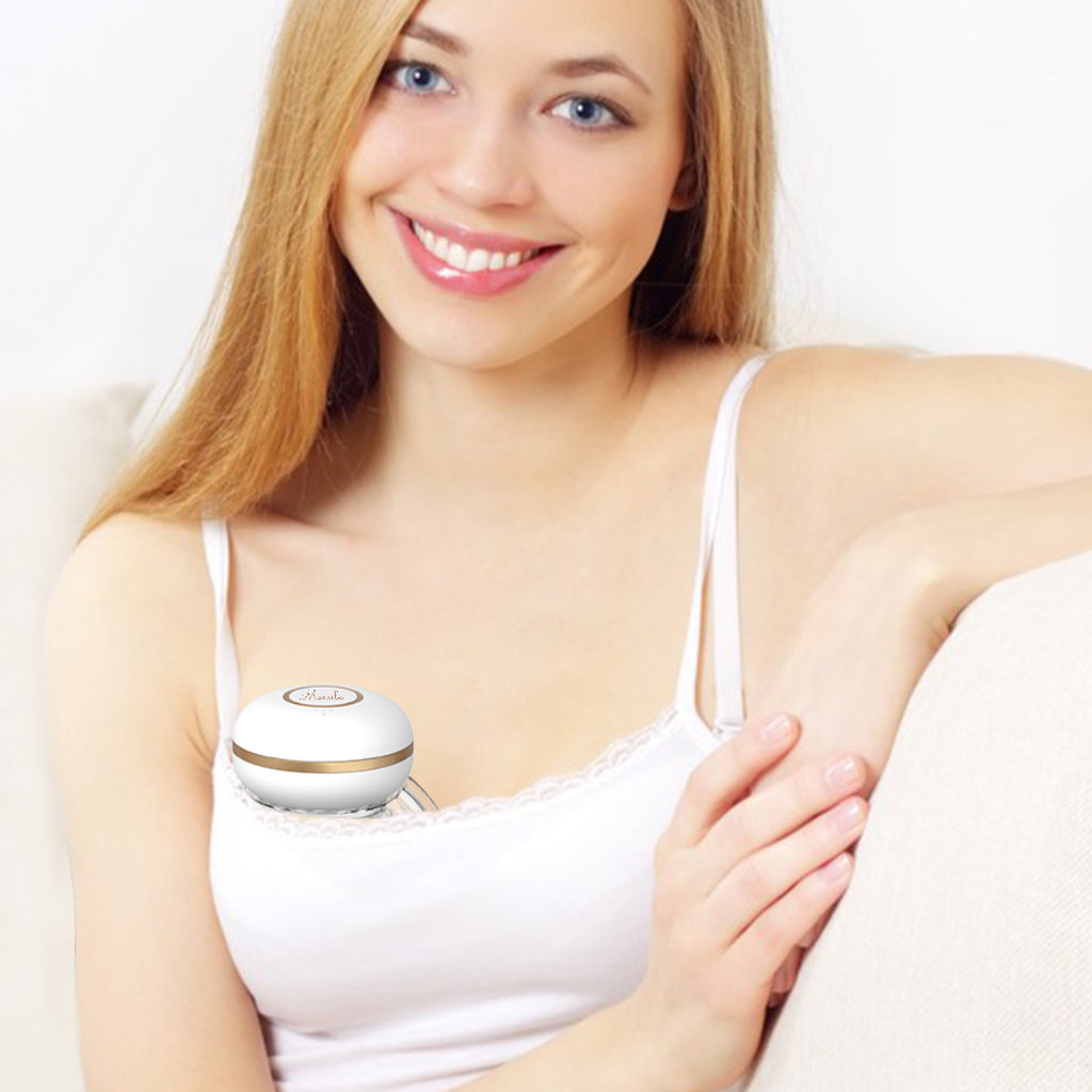 a woman wearing a mumilk pro breast pump while sitting on a couch